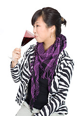 Image showing Asian woman drinking wine from purple glass