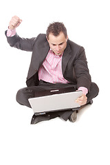 Image showing Young man with laptop sits on floor.