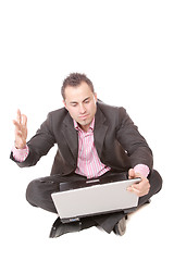 Image showing Young man with laptop sits on floor.