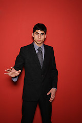 Image showing Young man in suit over red wall