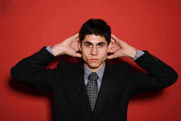 Image showing Young man in suit over red wall