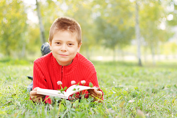 Image showing Boy with book laying on grass