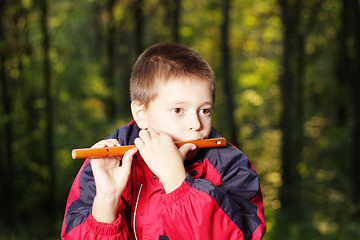 Image showing Kid playing fluite in dark forest