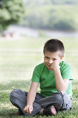 Image showing Boy in casual on grass leaning on fist