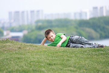 Image showing Boy in casual laying down on grass