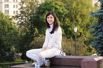 Image showing Smiling girl sitting on stone bench