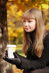 Image showing Blonde in black coat with cup