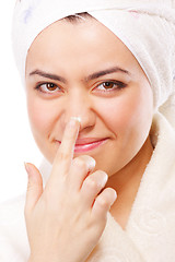 Image showing Smiling woman in bathrobe applying moisturizer
