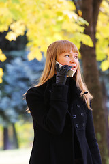 Image showing Blonde walks and talks on phone