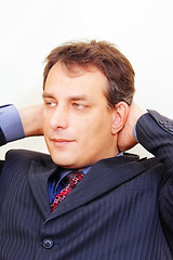 Image showing Serious businessman with hands behind head