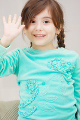 Image showing Little girl raises hand in greeting