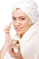 Image showing Woman in bathrobe applying moisturizer