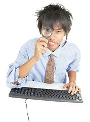Image showing Young Asian businessman peering thru magnifier