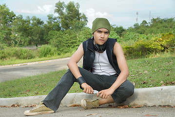 Image showing Suburban rapper sitting on street