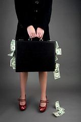 Image showing Woman holding briefcase overflowing with money