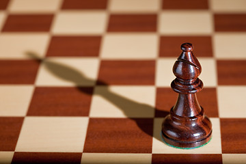 Image showing Chess piece - a black bishop on a chessboard.