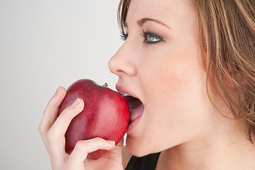 Image showing Beautiful girl biting red apple