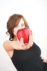 Image showing Beautiful girl holding a red apple, extended toward camera