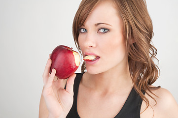 Image showing Beautiful girl biting off a piece of a red apple