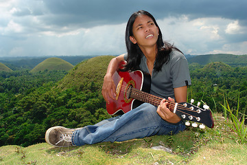 Image showing Pensive Asian hippie w guitar