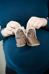 Image showing Pregnant mother holding baby booties