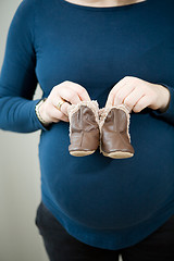 Image showing Pregnant mother holding baby booties