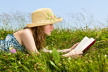 Image showing Young girl reading book in meadow