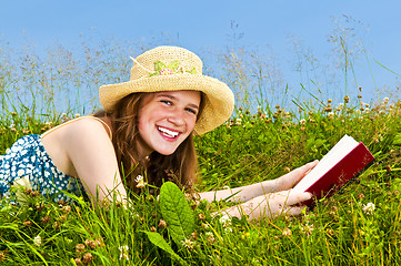 Image showing Young girl reading book in meadow