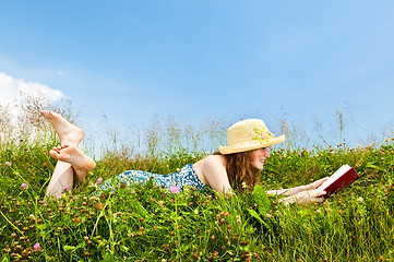 Image showing Young girl reading book in meadow