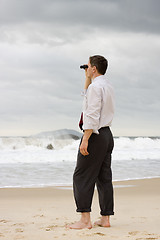 Image showing Businessman on a beach searching with binoculars