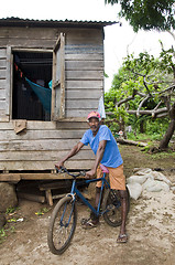Image showing editorial native man with bicycle in front of typical house corn