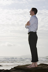 Image showing Businessman on a rock by the sea