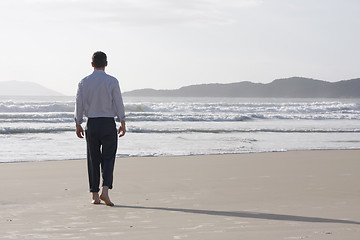 Image showing Businessman walking barefoot on a beach