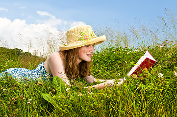 Image showing Young girl reading book in meadow