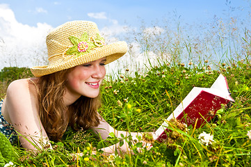 Image showing Young girl reading book in meadow
