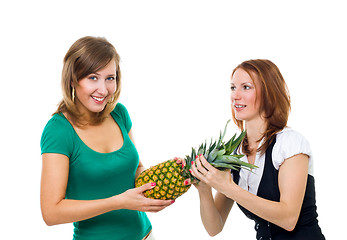 Image showing Two woman pull pineapple