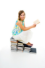 Image showing Woman reading book sitting on pile of them