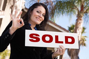 Image showing Attractive Hispanic Woman Holding Sold Sign In Front of House