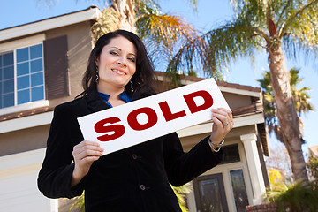 Image showing Attractive Hispanic Woman Holding Sold Sign In Front of House