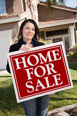 Image showing Hispanic Woman Holding Real Estate Sign In Front of House