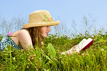 Image showing Young girl reading book in meadow