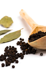 Image showing black pepper on wooden spoon and bay leaves