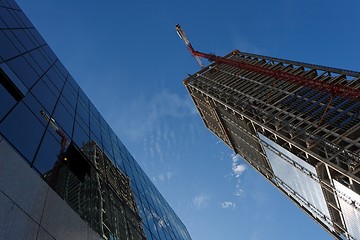 Image showing Lifting crane and high building under construction reflecting in another building