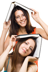 Image showing Two happy women friends with books play and smile