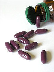 Image showing Big purple pills spilling from brown bottle.