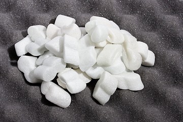 Image showing Heap of white shipping foam on black sheet of wavy foam rubber 