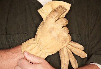 Image showing Man Putting on Leather Construction Gloves