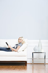 Image showing Young Woman Lying on Sofa Reading Book