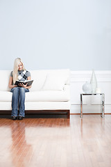 Image showing Young Woman Sitting on Sofa Reading Book