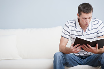 Image showing Young Man Sitting on Sofa Reading